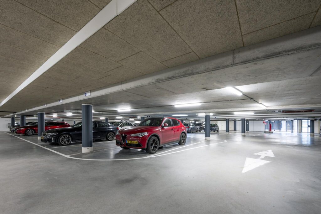 Ondergrondse parkeergarage aan de De Cuserstraat met geparkeerde auto's en duidelijke belijning.